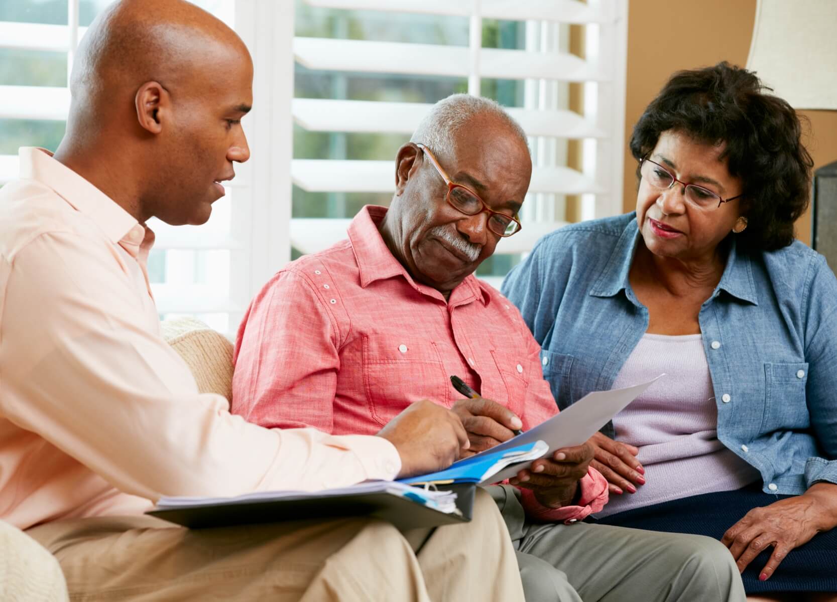 A financial advisor discussing paperwork with an elderly couple, assisting them with financial planning.