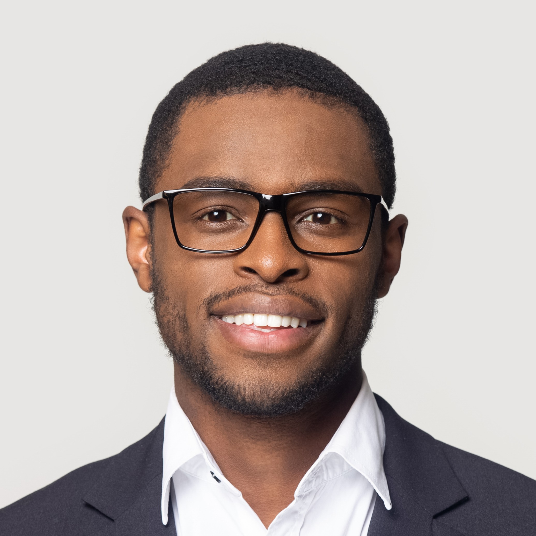 Smiling african American millennial businessman in glasses isolated on grey studio background posing, satisfied successful black male in formal suit wearing spectacles look at camera laughing