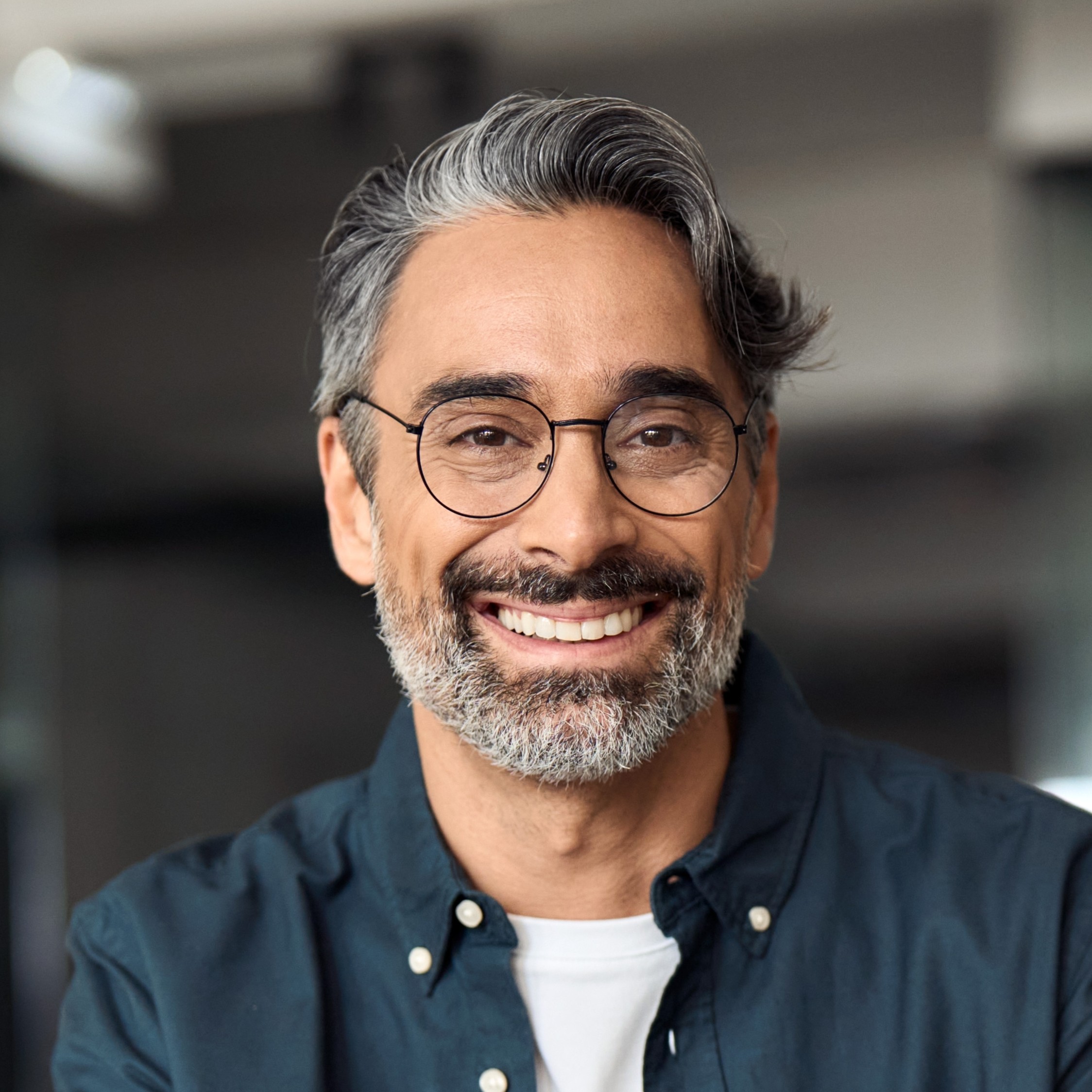 Happy middle aged professional business man, older executive ceo manager, smiling mature entrepreneur wearing glasses and shirt sitting at office desk working on laptop computer. Copy space. Portrait.