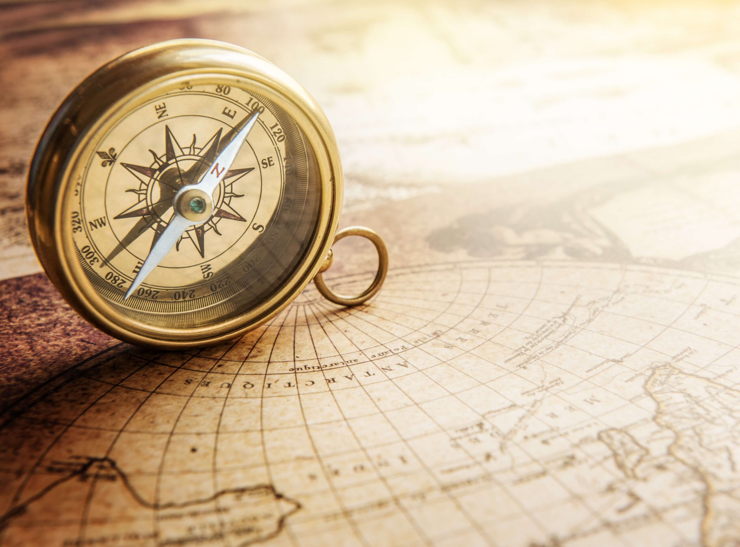 A vintage brass compass placed on an old-world map, symbolizing direction and exploration.