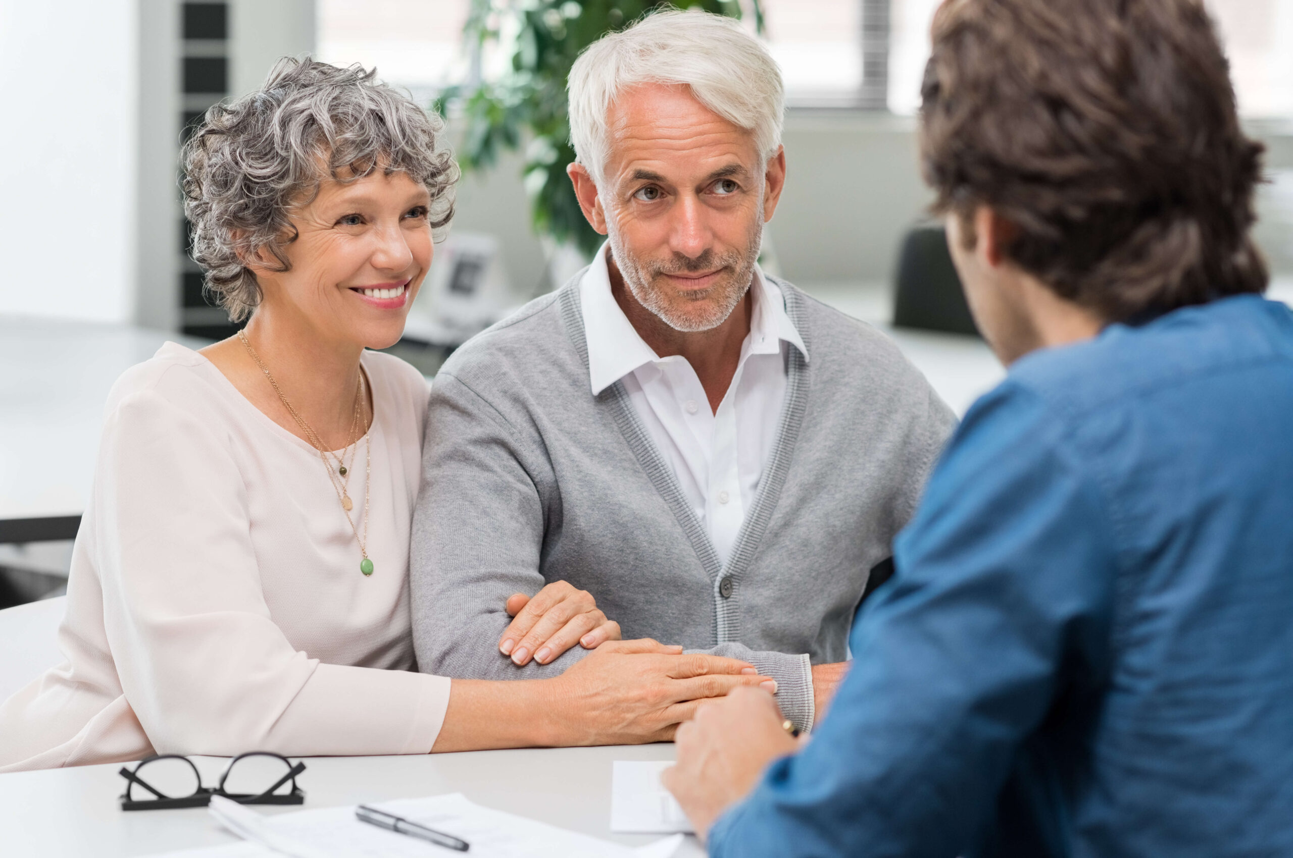 A senior couple discussing financial matters with a consultant at an office.