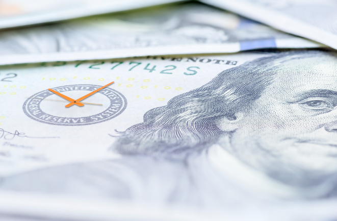 A close-up of a U.S. hundred-dollar bill with an overlay of a clock, symbolizing the concept of time and money.